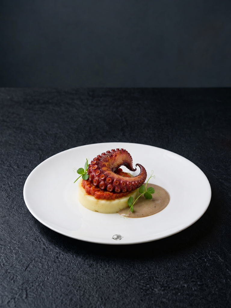 Poulpe rôti purée de pommes de terre, fine brunoise de poivron et de tomate, crème à l’ail noir.